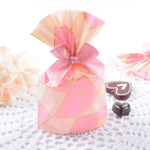 Pink and beige plaid cookie gift bags with ribbon bow on white lace mat