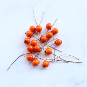 Artificial orange berry picks for DIY crafts on light marble surface 15 pieces