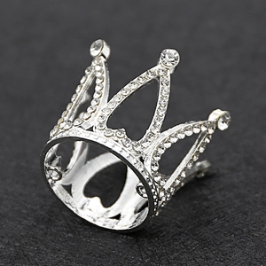 Detailed macro view of silver alloy crown with sparkling rhinestones on black surface