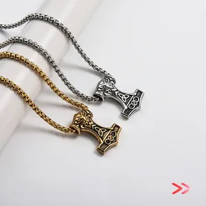 Detail of silver and gold Thor's Hammer pendants with box chain on display pedestal
