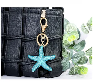 Detail of blue rhinestone starfish keychain with gold plating on black woven bag