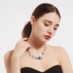 Detailed view of silver flower necklace with white pearls and black beads on a model