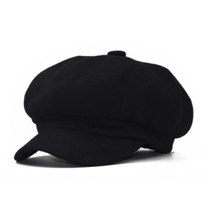 Detailed close-up of a classic black newsboy cap featuring 8-panel stitching and top button