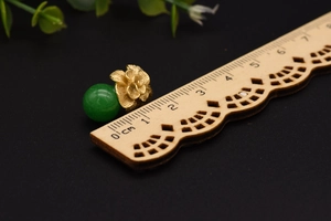 Detailed macro view of retro jade stone earring with gold flower carving on black background