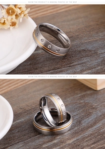 Detail of frosted stainless steel couple rings with rhinestones on a wooden background