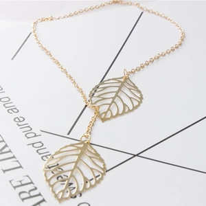 Detailed view of the gold hollow leaf pendant and delicate metal chain on white background