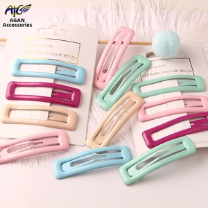 Detail of candy-colored rectangular metal hair clips on white feathered background