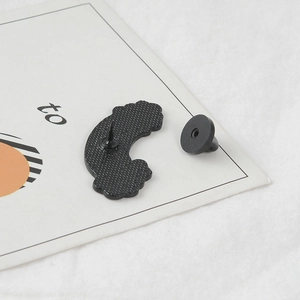 Detail view of the black enamel brooch back with a rubber pin clutch on white card