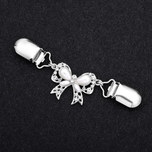 Dettaglio di una clip per cardigan a farfalla argento con perle bianche e strass lucidi