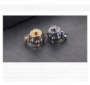 Macro shot of punk style clown face ring in gold and steel finish on black stone