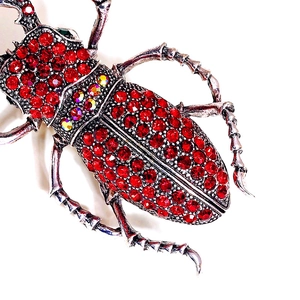 Détail de la broche scarabée de luxe avec strass rouges et base en métal argenté