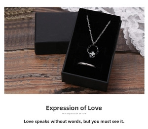 Parure de bijoux en argent avec pendentif trèfle et bague dans une boîte cadeau noire