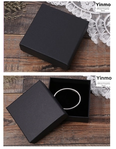 Gros plan sur un coffret cadeau noir mat avec bracelet jonc en argent sur bois