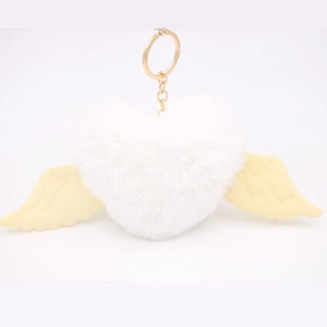 Detail shot of heart-shaped plush keychain with white wings and golden metal ring