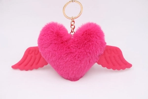 Close-up of fluffy pink heart keychain with plush wings and golden metal clasp details