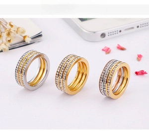 Detail view of triple-row zircon rings in gold and silver finishes with lifestyle props