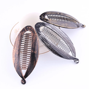 Detailed view of three vintage-style fish banana hair clips in bronze, silver, and gold