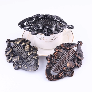 Detailed view of large black banana hair clips with elegant gold and silver floral patterns