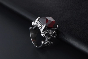 Macro view of gothic silver ring with red faceted gemstone and iris floral relief