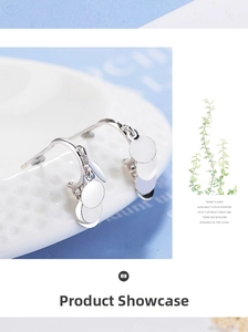 Macro detail of silver layered disc earrings hanging on a white textured ceramic plate