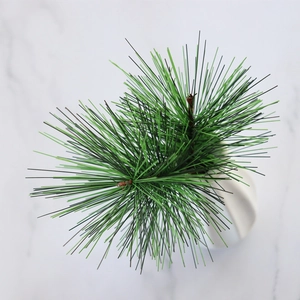 Detailed close-up of artificial green pine branches in a white vase for home decor