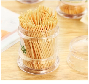 Bamboo toothpicks in transparent plastic container with lid on wooden table