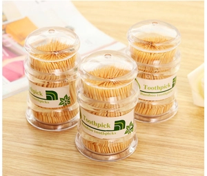 Three clear jars of disposable bamboo toothpicks displayed on a natural wood surface