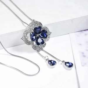 Detail of silver clover sweater necklace featuring dark blue crystals and rhinestone inlay