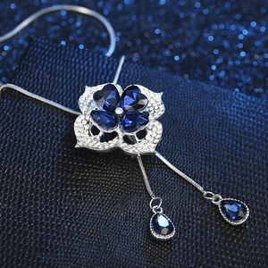 Floral necklace with deep blue heart-shaped gems and teardrop pendants on silver chain