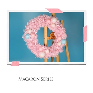 Pink macaron Christmas wreath with colorful PVC ornaments on a wooden easel stand