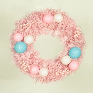 Pink Christmas wreath decorated with colorful macaron balls and berries on beige backdrop