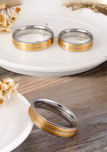 Detail of matte titanium steel couple rings featuring gold accents and small inlaid crystals