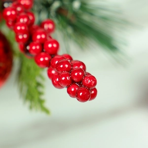 Artificial Christmas wreath with red berries, pine needles and shiny festive ornaments