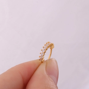 Macro-opname van goudkleurige blad helix piercing met micro-ingelegde zirkonia steentjes