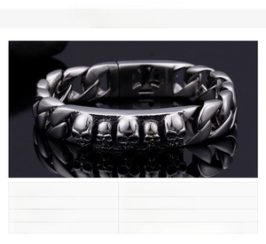 Detail of punk style stainless steel skull link bracelet with five embossed skull charms