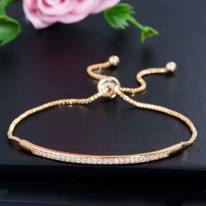 Elegant adjustable gold bracelet featuring a curved bar set with sparkling cubic zirconia