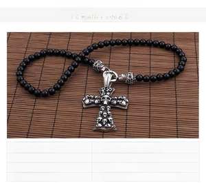 Macro shot of punk skull cross pendant with black glass beads and stainless steel detail