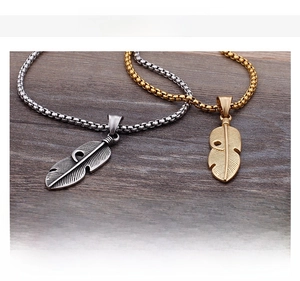 Detailed close-up showing texture of silver and gold feather pendants on box chains