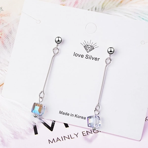 Long silver drop earrings with iridescent crystal cubes on a minimalist display