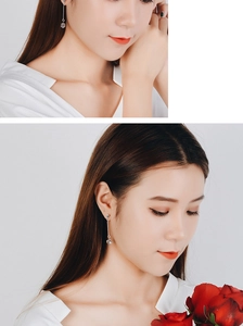 Detail view of silver linear drop earrings with crystal pendants on a model