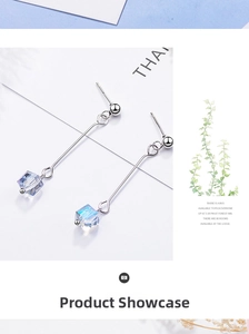 Close-up of long silver drop earrings with aurora cube crystals on white card