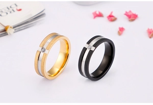 Close-up of gold and black brushed stainless steel rings with a single center zircon