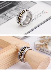 Detailed macro of a wide band ring with black inlay and zircons on a wooden stand