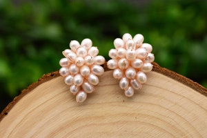 Close-up of pearl grape earrings on wooden surface with soft green background