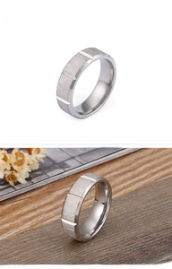 Close-up of matte silver stainless steel ring with horizontal brushed texture and grooves