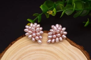 Macro detail of grape-shaped purple pearl earrings on a natural wood stump base