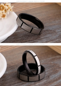 Macro detail of black frosted stainless steel rings with silver brushed accents on wood