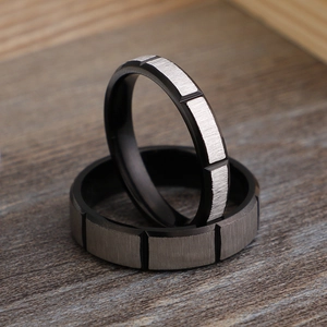 Brushed stainless steel black and silver pair rings on a textured wooden background