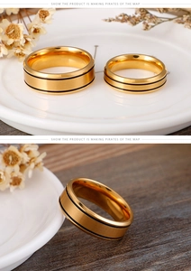 Detail of gold couple rings with black parallel lines on ceramic and wood background