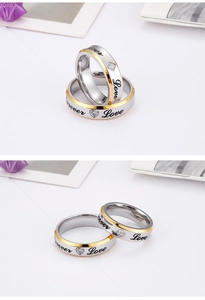 Detailed view of silver and gold couple rings with Forever Love engraving and zircon stones